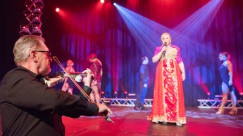 Opera singer Lisa Lockland-Bell centre stage as dancers perform a water ballet, accompanied by violin